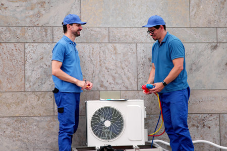 Hispanic HVAC Technician Repairs Heat Pump For Air Conditioning Service.の写真素材