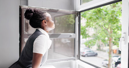 African American Woman Opens Window, Breathes In Fresh, Relaxing Air. She Stands At Her Home...