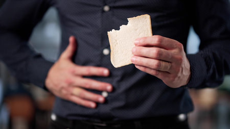 Young Man Grimaces In Pain After Eating Forbidden White Bread. Profession: Nutritionist.の写真素材