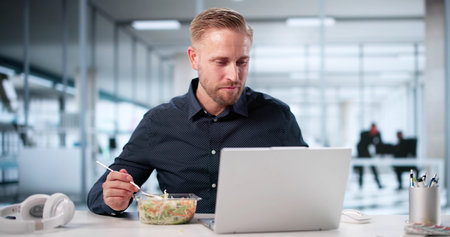 Busy Businessman Enjoys Healthy Lunch While Working On Computer At Office.の写真素材