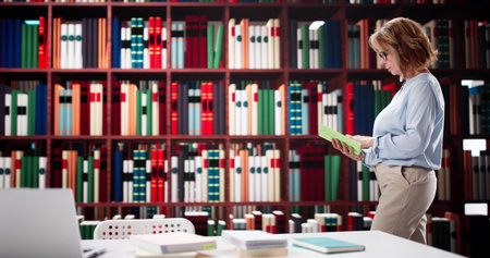 Senior Woman Leading Educational Research In University Library With Laptop.の写真素材
