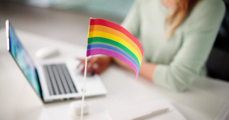 Diverse Workplace: Employee Using Laptop Next To Rainbow Flag