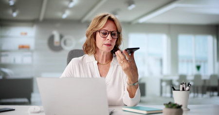 Professional Woman Juggling Calls And Computer Tasks In Home Office