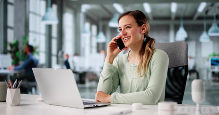 Young Businesswoman Smiling While Coaching Clients Remotely Via Computer And Phone.