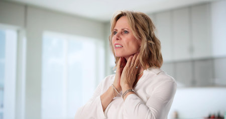 Senior Woman With Swollen Tonsil Glands And Throat Pain, Healthcare Professional.の写真素材