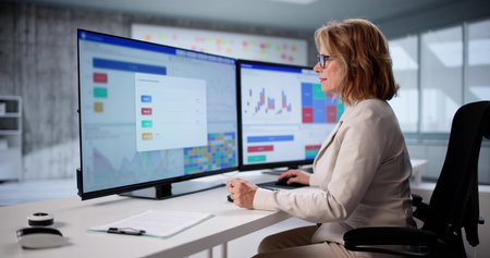 Senior Analyst Predicts Market Trends Using Financial Data On Computer. Elderly Woman Consults Analyticsの写真素材