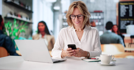 Woman Uses Phone App To Manage Finances In Coffee Shop.の写真素材