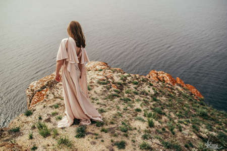 Young girl in a white dress in the meadow. Woman in a beautiful long dress posing on a meadowの写真素材