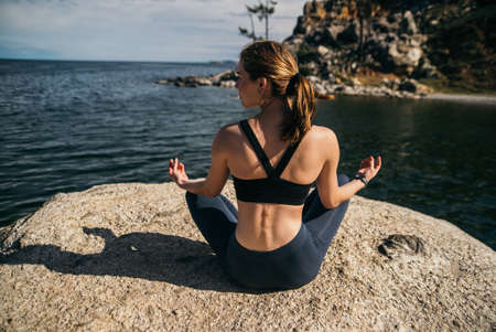 Young woman is practicing yoga at mountain lakeの写真素材