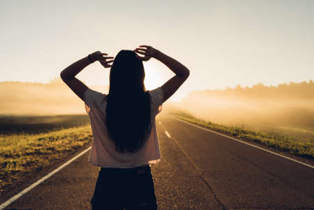 woman stand on the road with tree around, Asian traveler girl stand turn back on the road with sunshine and tree of parklandの写真素材