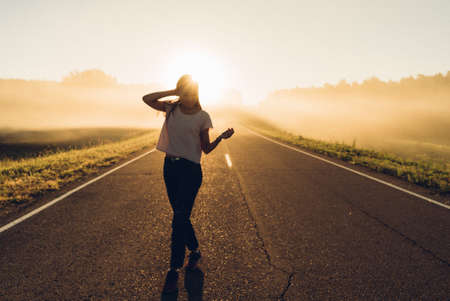 woman stand on the road with tree around, Asian traveler girl stand turn back on the road with sunshine and tree of parklandの写真素材