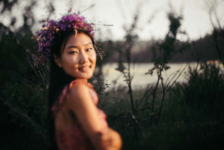 Happy young woman in a wreath from wildflowers and grass. Cute girl with summer flowers, closeupの写真素材