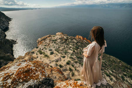 Beautiful young woman outdoor on the hill on a summer day, against blue sky with clouds