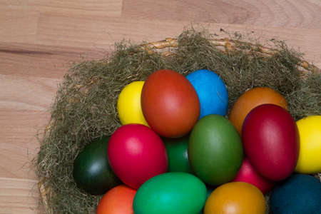 Colorful eggs in the nest, on wooden surface