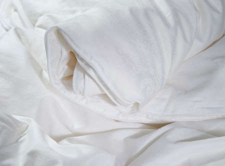 white roll up silk blanket on bed