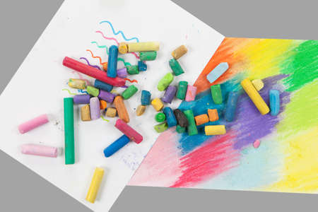 stack of multicolored pastel chalks on white papers isolated on gray backgroundの写真素材