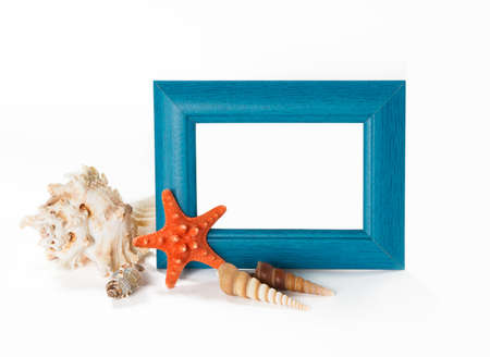 Blue photoframe with seashells near it, isolated on white backgroundの写真素材