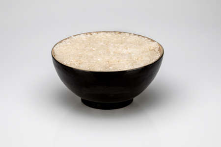 Black bowl with rice, isolated on white background.の写真素材