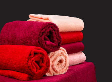 stack of colorful terry towels on a table isolated on dark backgroundの写真素材