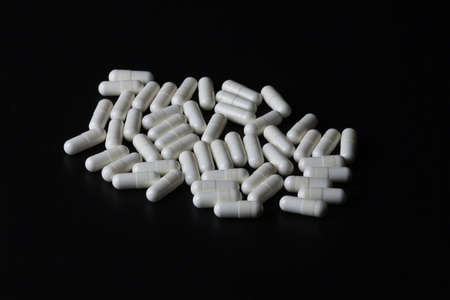 stack of white medicine pills on black backgroundの写真素材