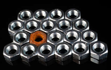 set of new nuts and one rusty nut on a black mirror background