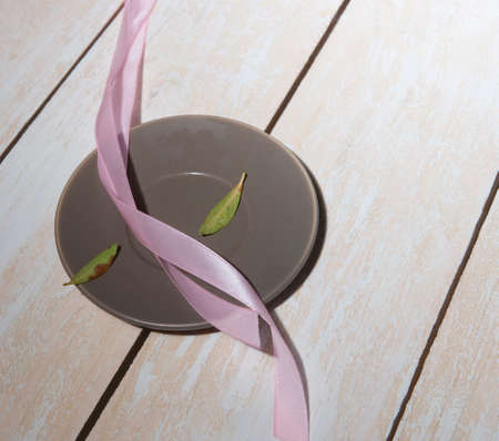pink ribbon on saucer. on wooden backgroundの写真素材