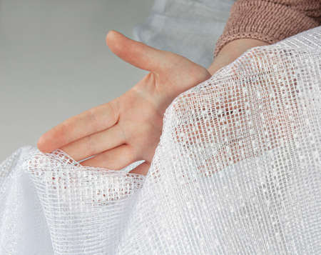 female hands hold a transparent curtain. macro and texture of white tulleの写真素材