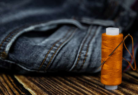 Threads and needle on jeans background, wear repair concept.の写真素材