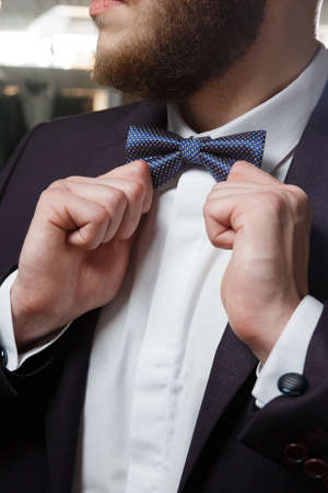 close-up of part of stylish dark blazer, white shirt, waistcoat and bow tie.