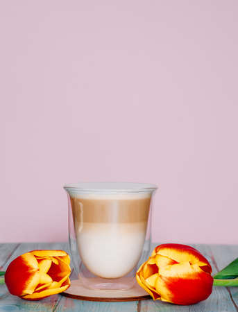 Hot coffee latte or cappuccino on a pink delicate background copy space. Latte with milk in a...