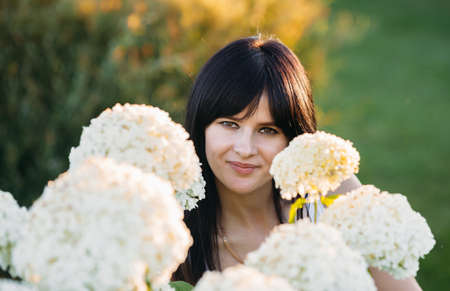 beautiful young brunette in a meadow with white flowers on a warm summer day