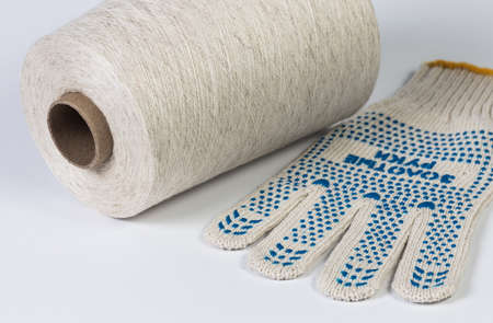Spool of cotton thread and work glove on white background.