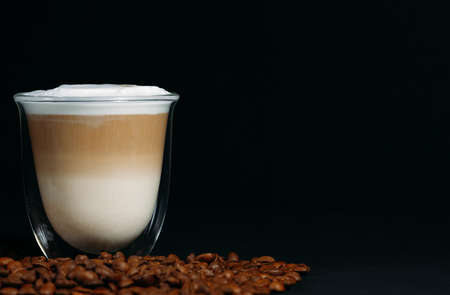 Close-up of a special glass transparent thermo cup with cappuccino. Beautiful layers of milk and...