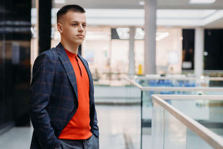 A handsome young man in a suit stands indoors and looks to the side. Beautiful stylish portrait.