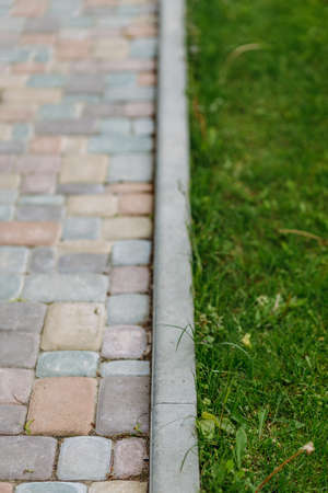 The border of a brick path or sidewalk with a green lawn. Vertical view.の写真素材