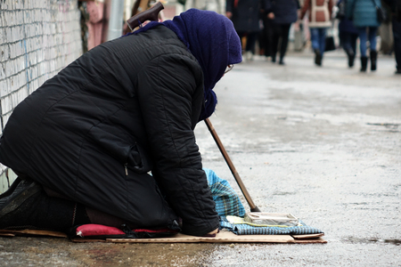 Moscow.Russia.-January 2018.Sad homeless woman sitting on the street people passing by.のeditorial素材