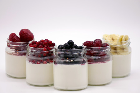 Fresh berries in the jar with the yogurt. On white background. Fruit yogurt.の写真素材