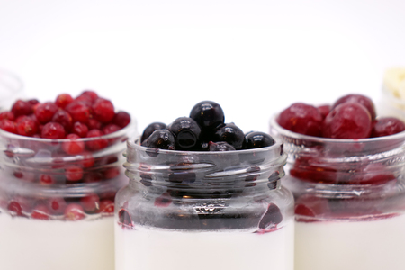 Fresh berries in the jar with the yogurt. On white background. Fruit yogurt.の写真素材