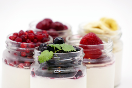 Fresh berries in the jar with the yogurt. On white background. Fruit yogurt.の写真素材