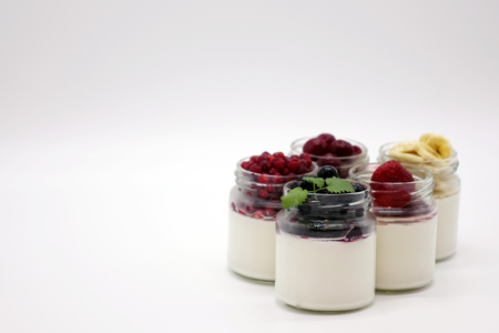 Fresh berries in the jar with the yogurt. On white background. Fruit yogurt.の写真素材