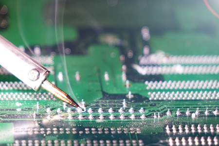 Soldering to a circuit Board of a computer close up.Electronic technology.の写真素材