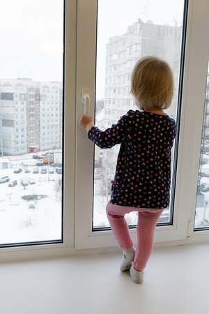 A little girl stands on the window sill.One of the house.の写真素材