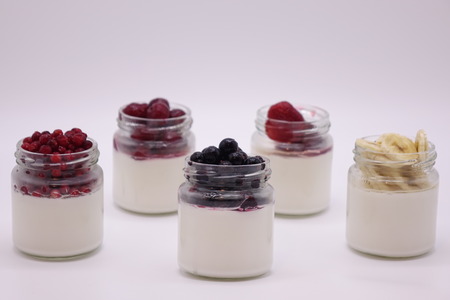 Fresh berries in the jar with the yogurt. On white background. Fruit yogurt.の写真素材