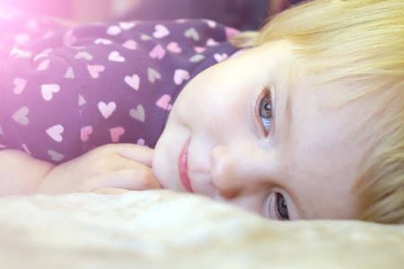 Beautiful child lying on the bed.の写真素材