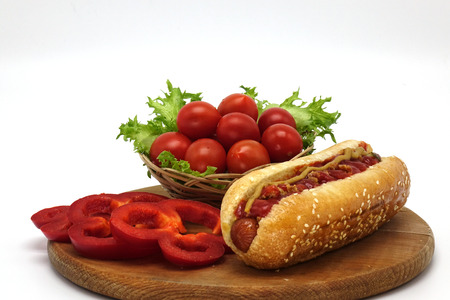 Hot dogs and French fries on white background. Sausages with tomato sauce and cherry tomatoes on a wooden Board.の写真素材
