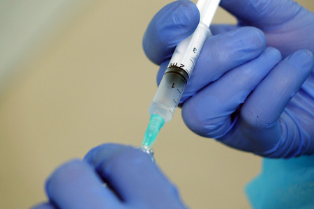 The nurse draws the solution into the syringe from the bottle in the office of the clinic.Medical syringe.の写真素材