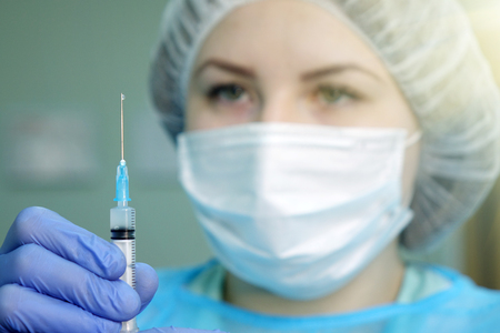 The nurse draws the solution into the syringe from the bottle in the office of the clinic.Medical syringe.の写真素材