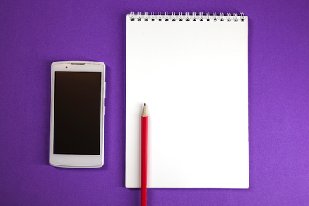Notepad, pencil and phone on colored background top view, school, business, education, knowledgeの写真素材