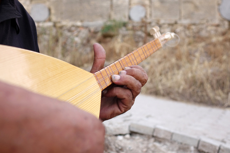 A man in a white hat plays a game of baglama.の写真素材