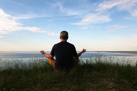 Man sitting in a Lotus position on top of a hill .の写真素材